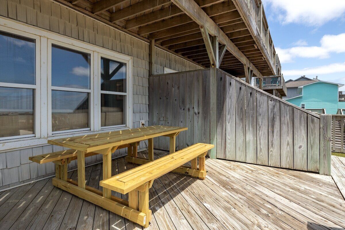 A wooden deck with a picnic table and a wooden fence.