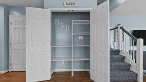 A corner pantry with open doors, a staircase, and a 'PANTRY' sign above. - Shore Thing West -Spacious Beachfront Oasis & Pool - 5BR (Emerald Isle)
