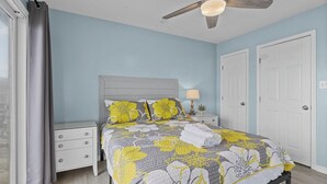 A bedroom with a bed, nightstands, a ceiling fan, and a window with curtains. - Shore Thing West -Spacious Beachfront Oasis & Pool - 5BR (Emerald Isle)