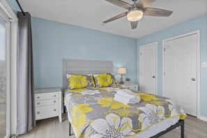 A bedroom with a bed, nightstands, a ceiling fan, and a window with curtains. - Shore Thing West -Spacious Beachfront Oasis & Pool - 5BR (Emerald Isle)