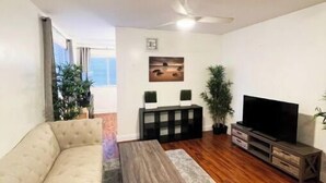 Una sala de estar con sofá, mesa de centro, mueble para televisor y ventilador de techo.