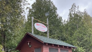 A small red cabin with a sign that reads "Mac's Camp Live Bait Welcome." - Kagawong Blue (Spring Bay)