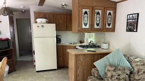 A compact kitchen with wooden cabinets, a refrigerator, a stove, and a microwave. - Kagawong Blue (Spring Bay)