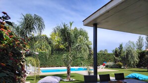 Un patio con piscina, mobiliario exterior y diversas plantas.