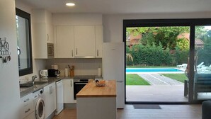 Une cuisine moderne avec des meubles blancs, un lave-linge encastré et un îlot central en bois.