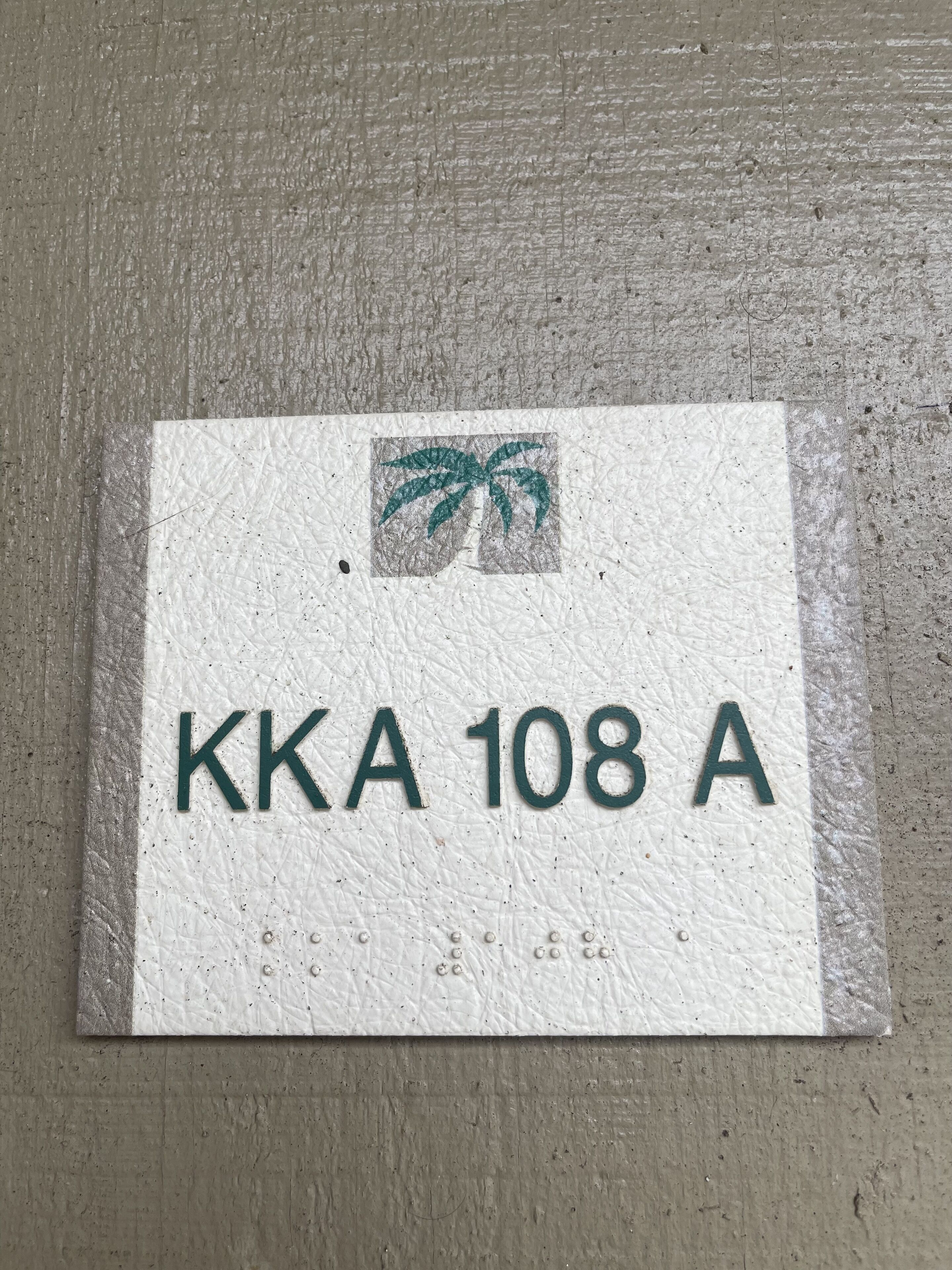 Un panneau portant l’inscription « KKA 108 A » et un symbole représentant un palmier.