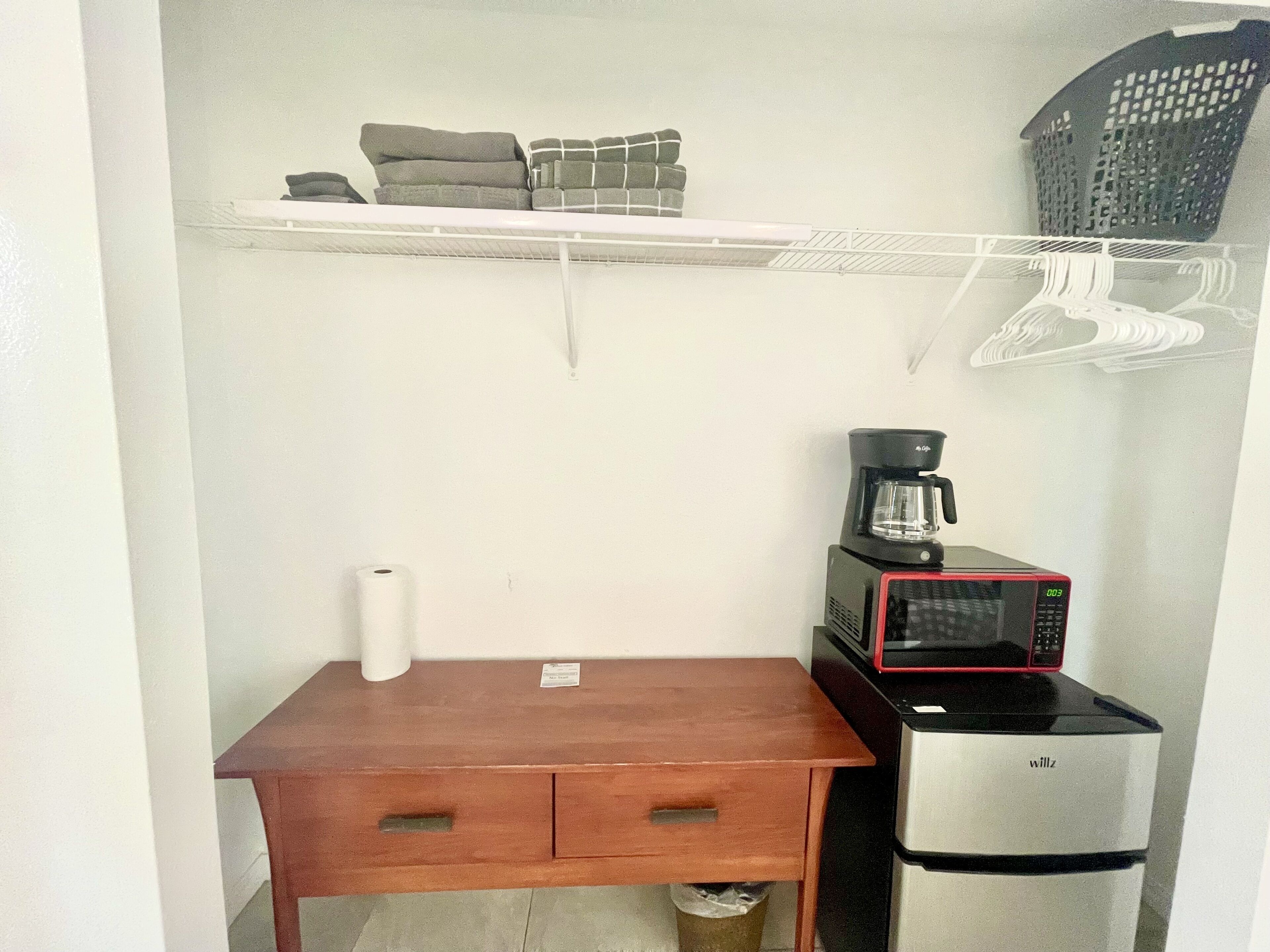 A compact kitchenette with a microwave, coffee maker, and a small wooden table.