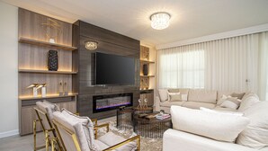 Una sala de estar moderna con un televisor de pantalla plana, una chimenea, un sofá y una mesa de centro.