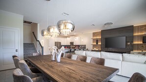 Una cocina moderna con un comedor amplio, electrodomésticos integrados y un televisor montado en la pared.