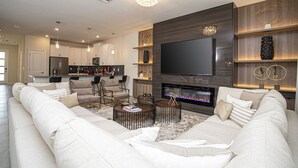Una sala moderna con un televisor de pantalla plana grande, una chimenea y un rincón de estar acogedor.