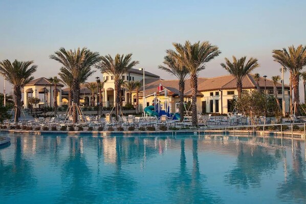 Relax by the pool surrounded by palm trees and Mediterranean-style architecture.