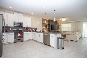Enjoy cooking in this well-equipped kitchen with stainless steel appliances, white cabinetry, and a central island with a sink.