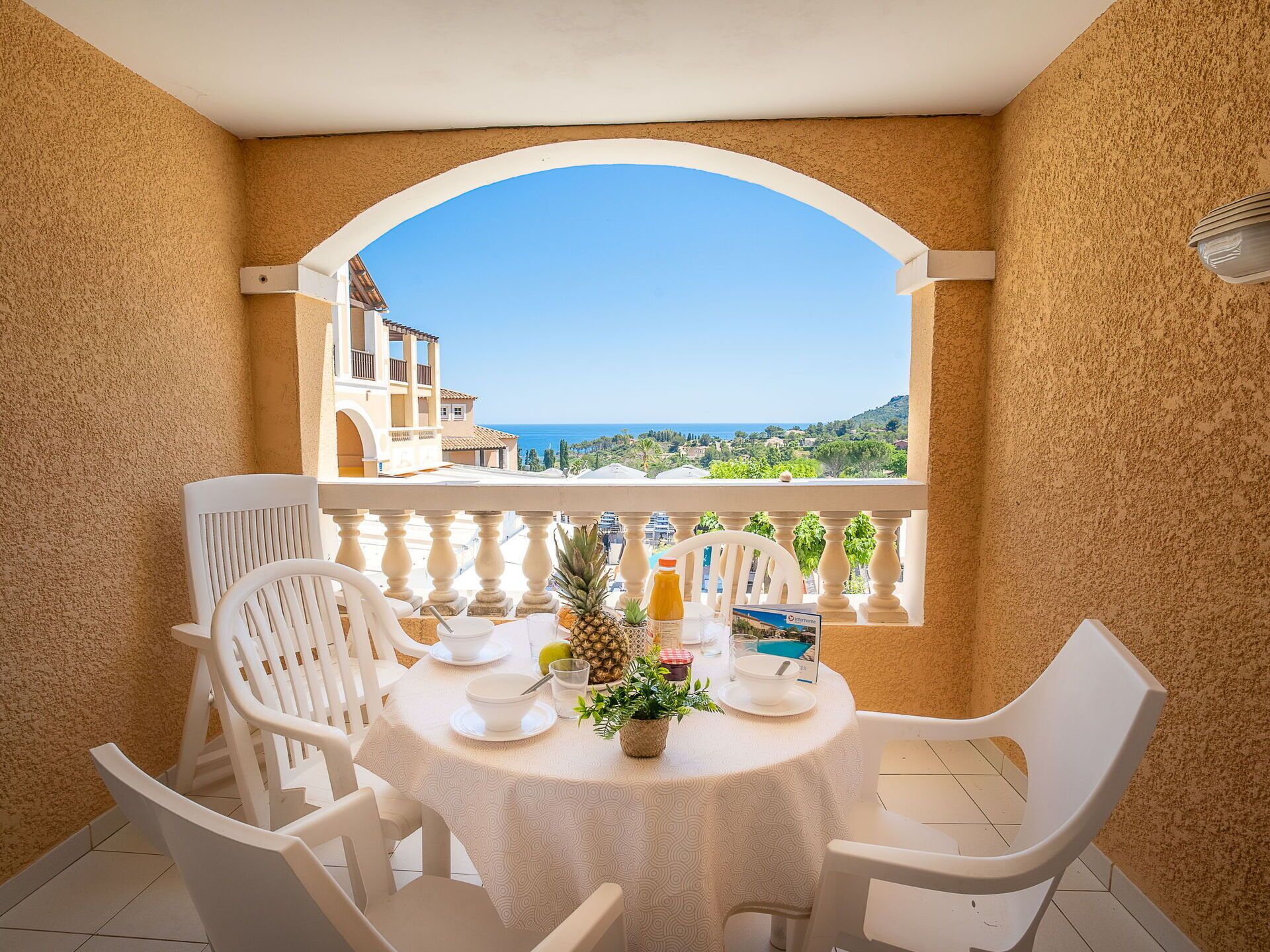 Ein Balkon mit Tisch für Zwei, mit Blick auf eine malerische Aussicht auf Meer und Gebäude.