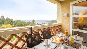 A balcony with a table set for breakfast, overlooking a scenic view of the sea and greenery. - Nice apartment for 5 people with A/C, pool, WIFI, TV, patio and pets allowed (Saint-raphaël)