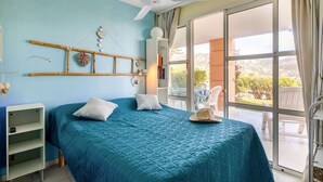 A bedroom with a bed, a ceiling fan, a window, and a view of the outdoors. - Nice apartment for 5 people with A/C, pool, WIFI, TV, patio and pets allowed (Saint-raphaël)