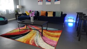 A modern living room with a dark blue sofa, colorful cushions, a glass vase with flowers, a vibrant striped rug, and abstract wall art. - The Heart of Raleigh (Raleigh)
