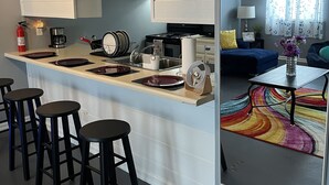 A modern kitchen with a central island, bar stools, a coffee maker, and a fire extinguisher. - The Heart of Raleigh (Raleigh)