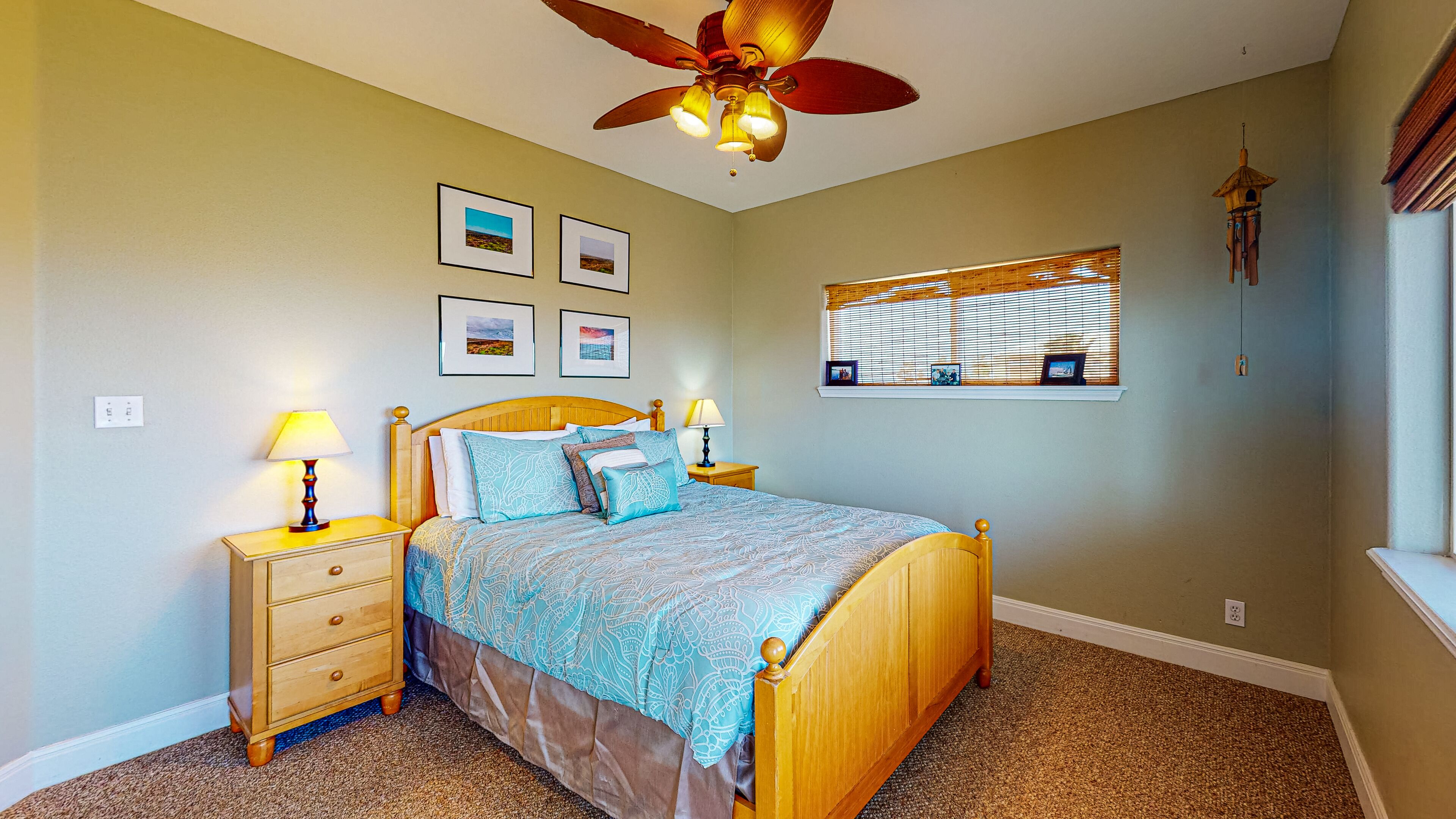 A bedroom with a bed, two bedside tables with lamps, a ceiling fan, and a window with blinds.
