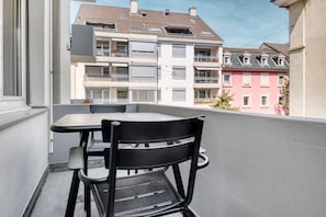Ein Balkon mit Tisch und Stühlen, der auf eine Reihe von mehrstöckigen Gebäuden mit Balkonen blickt.