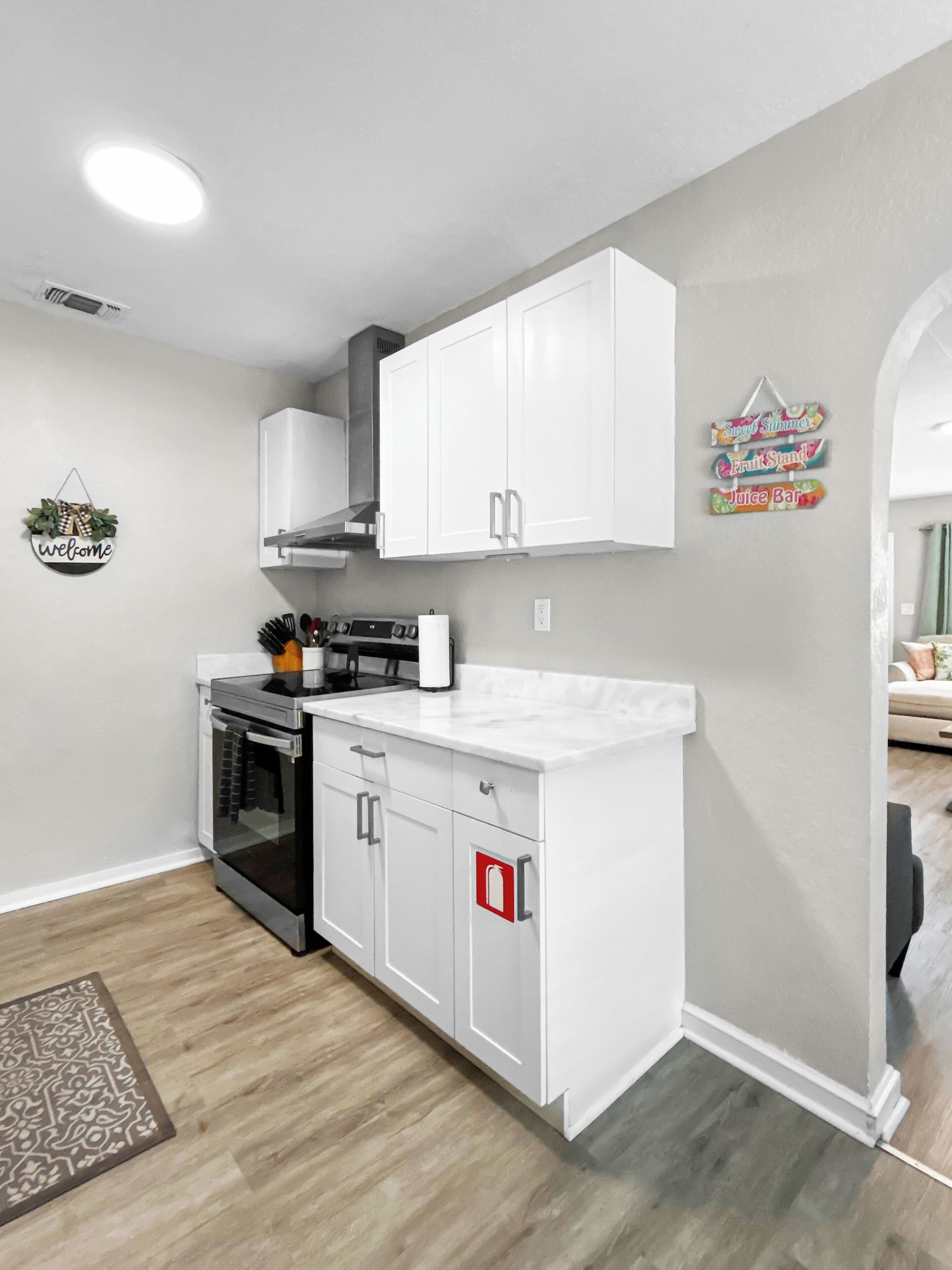 A modern kitchen with white cabinetry, a built-in oven, and a stainless steel range hood.