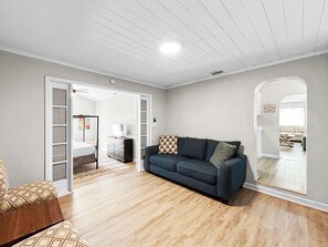 A living room with a dark blue sofa, a wooden floor, and a white ceiling. - The Pink Pearl (St. Petersburg)