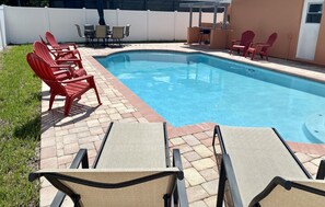 A swimming pool with red Adirondack chairs and beige lounge chairs. - The Pink Pearl (St. Petersburg)