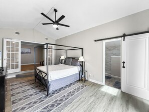 A bedroom with a four-poster bed, a ceiling fan, and a door leading to a bathroom. - The Pink Pearl (St. Petersburg)