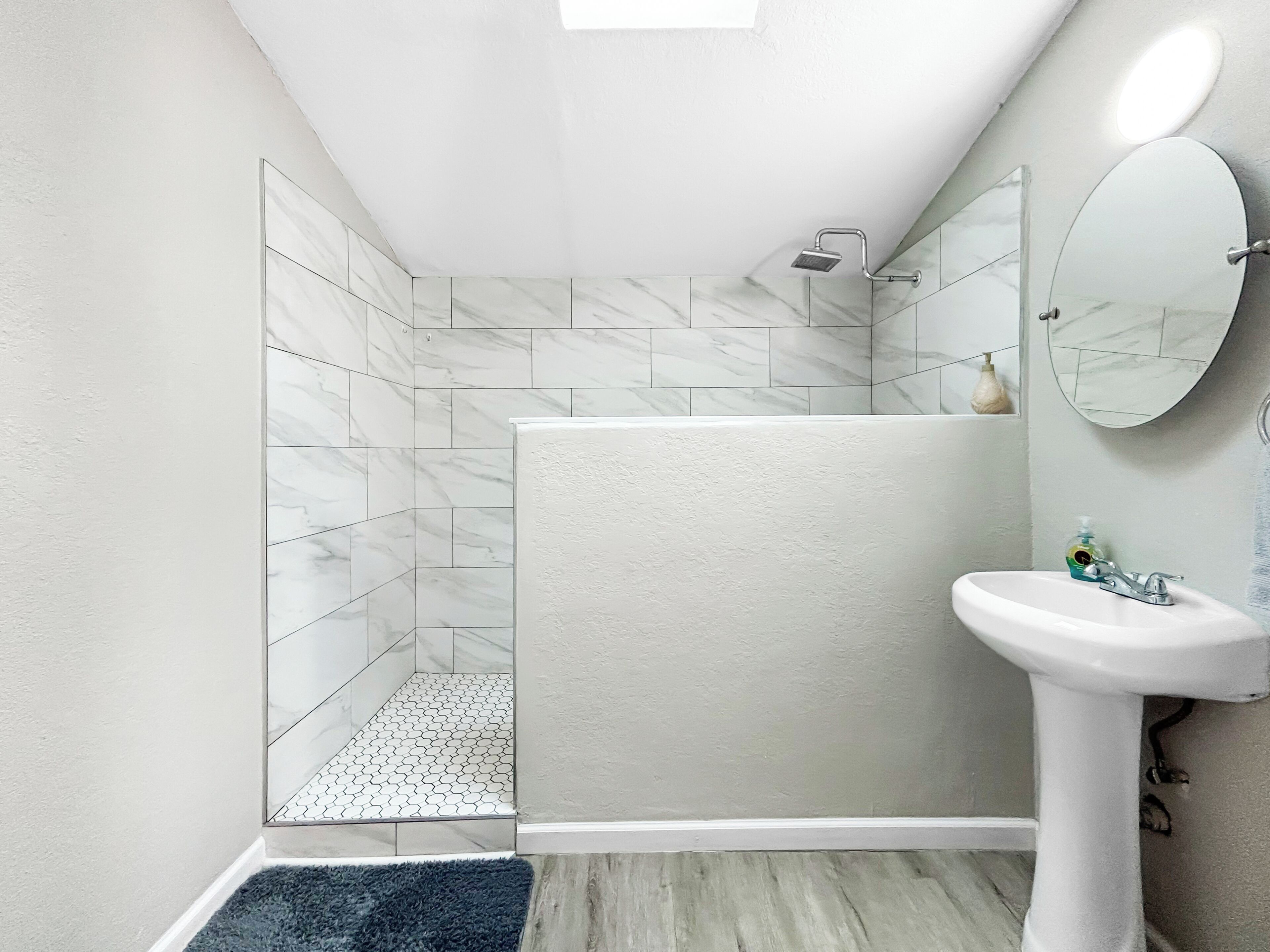 A modern bathroom with a shower, a sink, and a mirror.