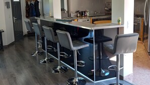A modern kitchen with a central island, bar stools, and a built-in oven. - Vacation home 5 minutes from the beach (Agde)