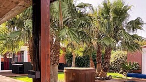 A backyard with a swimming pool, wooden deck, and palm trees. - Vacation home 5 minutes from the beach (Agde)