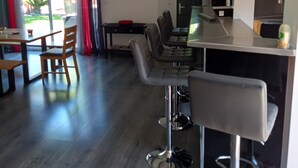 A modern kitchen with a bar area, wooden dining table, and chairs. - Vacation home 5 minutes from the beach (Agde)