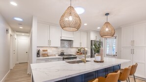 A modern kitchen with white cabinets, a marble island, and two pendant lights. - Gem in Heart of Old Town Scottsdale  (Scottsdale)