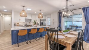 A modern kitchen with white cabinets, a blue island, and orange bar stools. - Gem in Heart of Old Town Scottsdale  (Scottsdale)