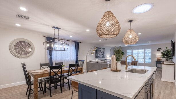 A modern kitchen with a central island, pendant lights, and a dining area with chairs and a table. - Gem in Heart of Old Town Scottsdale  (Scottsdale)