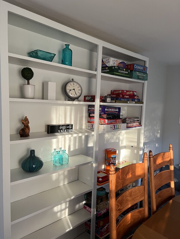 A room with a white bookshelf containing various board games, a clock, and decorative items. - Modern Farmhouse, Sleeps 8, North of St. Joseph (Benton Harbor)