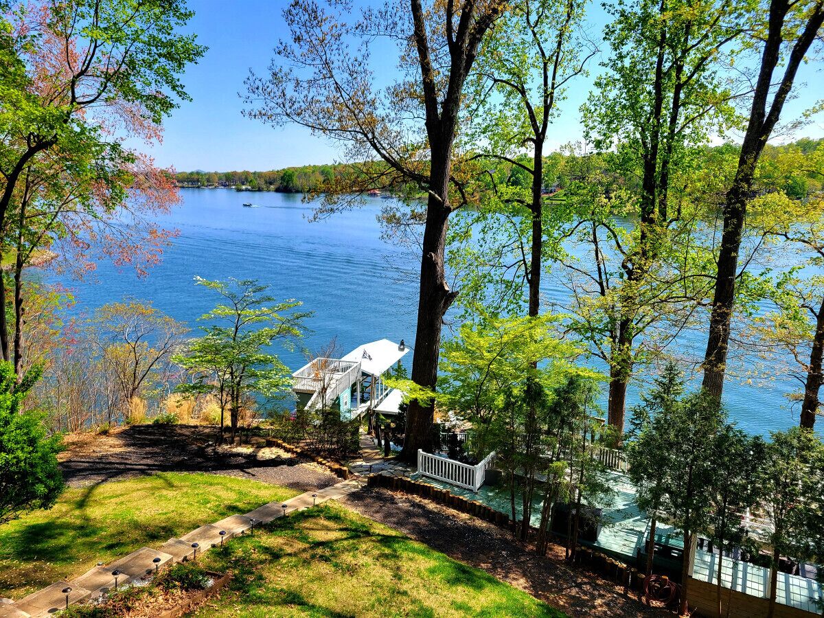 A lakeside property with a dock, a white building with a deck, and a fenced area.