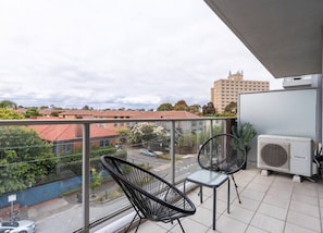 Ein Balkon mit zwei Stühlen, einem Tisch und einer Klimaanlage.