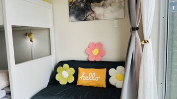Un dormitorio acogedor con cama, ventana con cortinas, luz fijada en la pared y un tapiz floral decorativo.