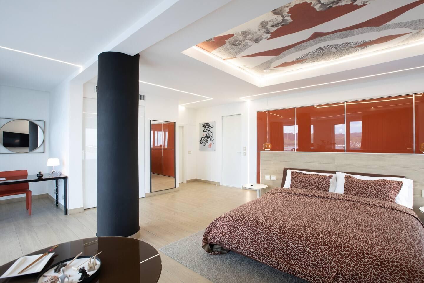 A modern hotel room with a large bed, a desk, and a mirror.