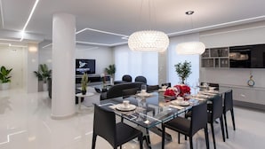 A modern dining area with a glass table, black chairs, and a chandelier. - Serenity Penthouse - The Pinnacle of Luxury (Maho)