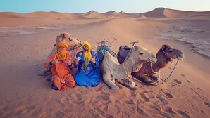 A desert landscape with sand dunes and camels.