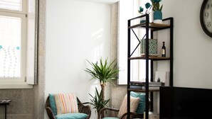 A cozy living room with wicker chairs, a bookshelf, and a large window.