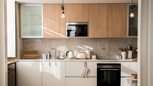 A modern kitchen with white cabinets, a built-in oven, and a microwave.