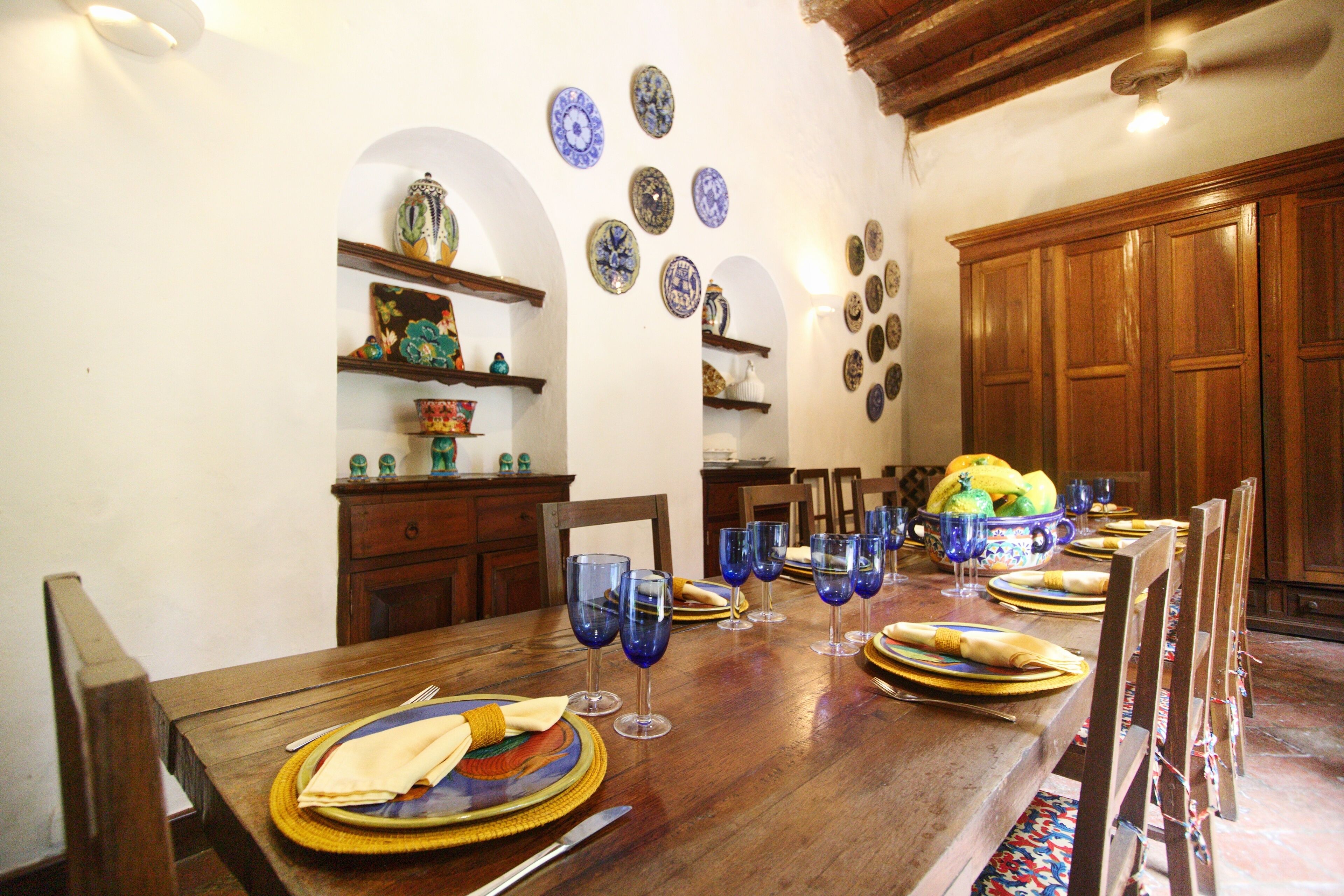 A dining table set with plates, glasses, and a bowl of fruit.