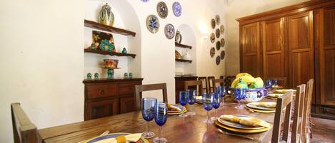 A dining table set with plates, glasses, and a bowl of fruit.