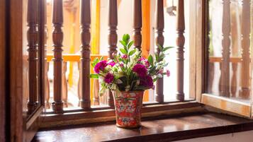 Una ventana con barandilla de madera y un florero con flores sobre un alféizar de madera.