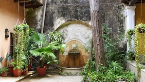 A courtyard with potted plants, a stone fountain, and a tree. - Casa Baloco (Cartagena)