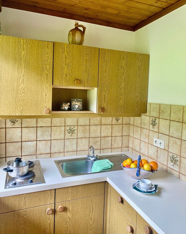 Uma cozinha com armários de madeira, pia, fogão e painel de azulejos.