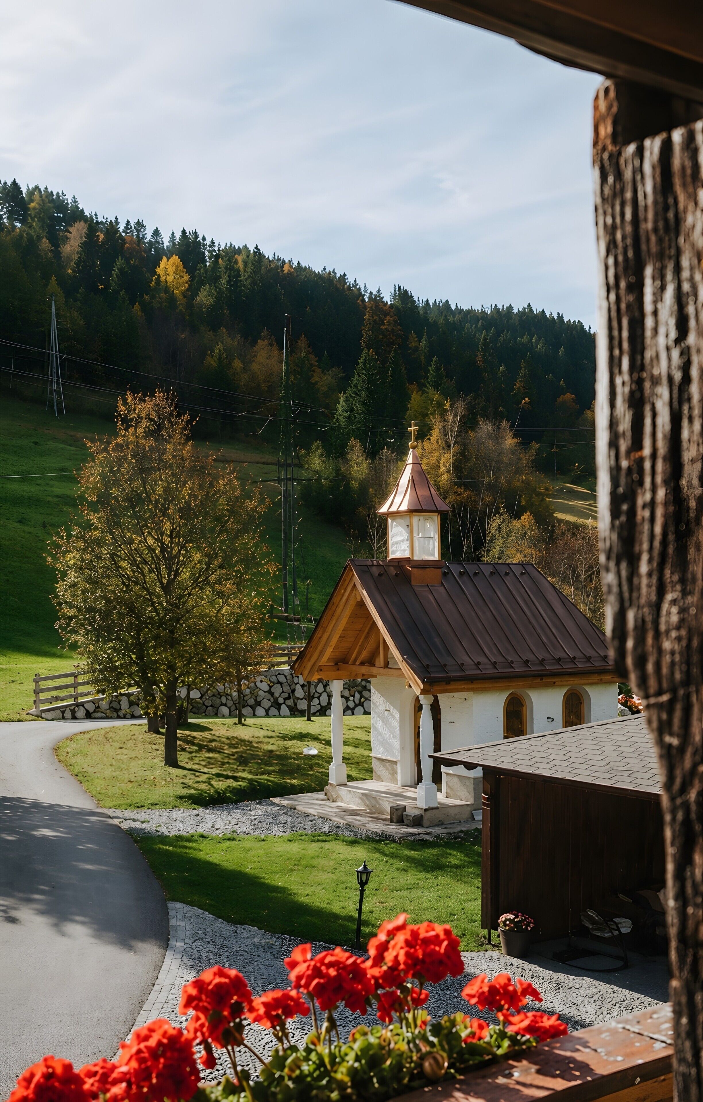 En lille kirke med et klokketårn, omgivet af en murstensmur og en anlagt sti.