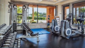 Un gimnasio con máquinas de pesas, cintas de correr y una colchoneta azul.